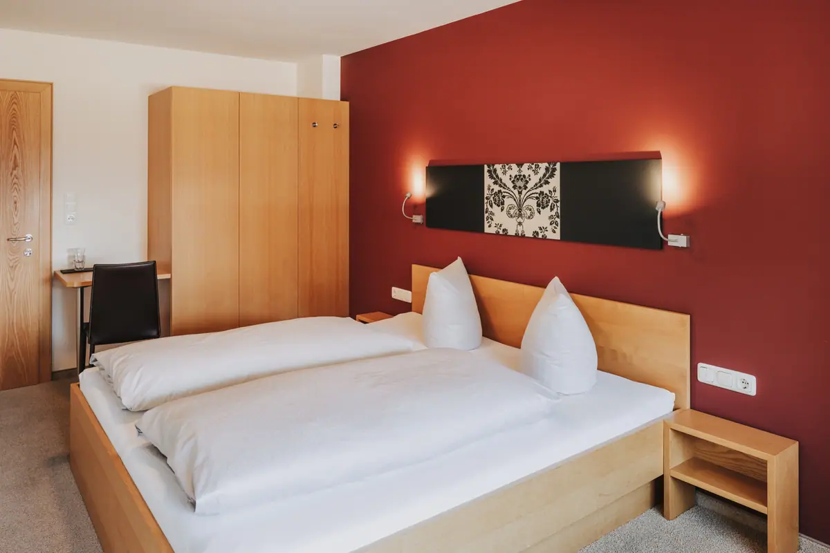 Doppelzimmer mit roter Wand und Leselampen